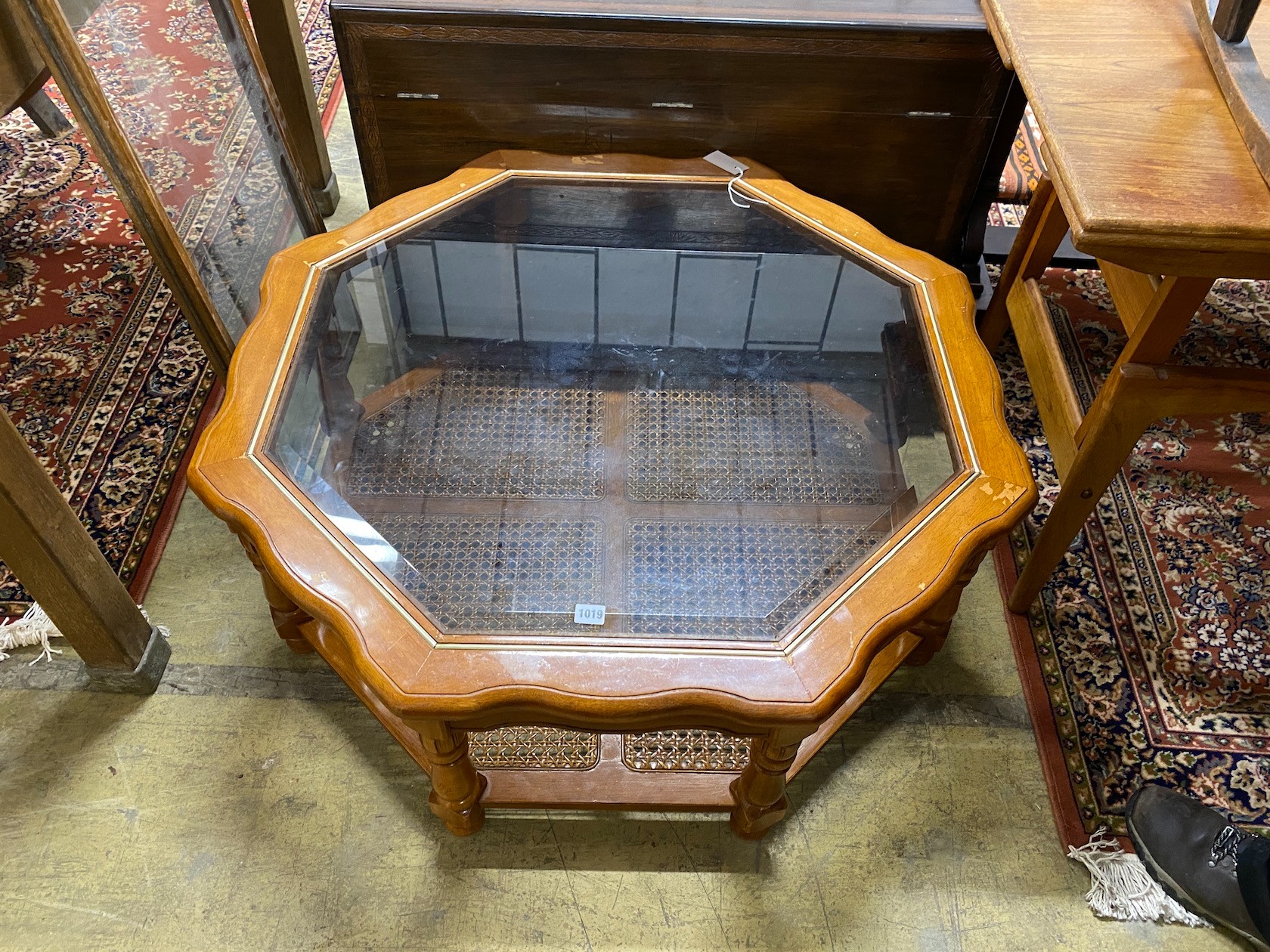 A modern octagonal brass mounted walnut glass top coffee table with caned undertier, diameter 100cm, height 40cm.